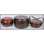 A collection of three Chinese lidded Lacquered food carriers, the largest with removable lid and