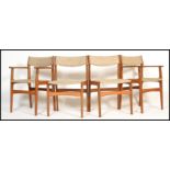 A set of 4 mid century teak wood dining chairs being raised on shaped legs with original wool