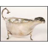 An early 20th century silver hallmarked sauce gravy boat raised on hoof feet with flared rim and