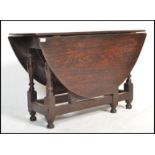 An 18th century solid country oak peg jointed drop leaf / gate leg dining table being raised on