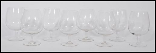 A set of eight glass large brandy glasses raised on circular foot with cylindrical stem and large