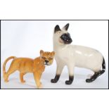 A vintage Beswick ceramic figure modelled as a lioness along with a Royal Doulton figurine of a cat.