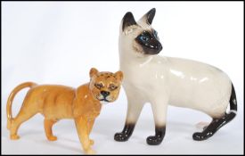 A vintage Beswick ceramic figure modelled as a lioness along with a Royal Doulton figurine of a cat.