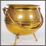 A 19th century Victorian large brass cauldron raised on three bun feet and tapering legs. Swing