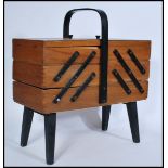 A vintage retro 20th century teak wood metamorphic sewing box raised on ebonised supports complete