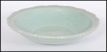 A Chinese celadon glaze bowl of scalloped form having floral motifs and decoration. Measures 5cm-