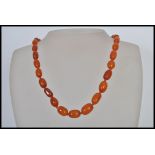 A vintage amber bead necklace having a yellow metal clasp with 31 hand knotted graduating amber