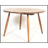 A mid century Ercol circular coffee table being raised on turned tapering legs with chamfered edge