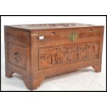 A mid 20th century Chinese camphor wood blanket box chest with carved, detailed scenes in relief