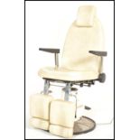 A retro 20th Century Dental / Dentist adjustable chair, white faux leather upholstery raised on a