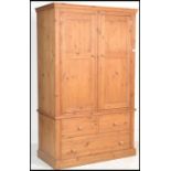 An antiques style large country pine double wardrobe. Raised on a plinth base with drawers having