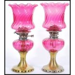 A pair of 19th Century Victorian oil lamps having cranberry glass shades with fanned rims and