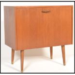 A 1970's teak wood record / 12" vinyl cabinet being raised on tapering legs with fall front and