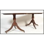 An Edwardian mahogany pedestal line inlaid dining table. Raised on reeded splayed leg twin columns