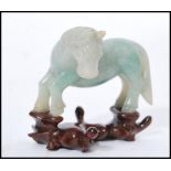 A vintage 20th century Chinese carved green jade figurine of a horse raised on carved wooden socle