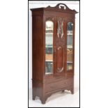 An Edwardian Art Nouveau walnut single wardrobe. Raised on a plinth base with drawer having mirror