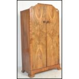 A 1930's Art Deco walnut wardrobe. Shaped feet with twin full length panel doors enclosing a