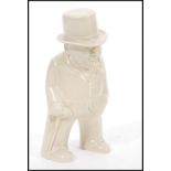 A 20th Century Bristol pottery figurine of Winston Churchill smoking a cigar having a cream glaze.