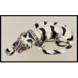 A silver brooch in the form of a cat having enamelled black and white colouring set with