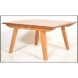 A beech and elm low coffee table having a plank top raised on angled tapering legs. The table up-