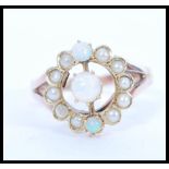 An early 20th Century 9ct gold ring set with a round opal with two smaller accent opals and a halo