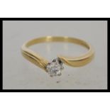 A hallmarked 18ct gold and solitaire crossover diamond ring, prong set with a brilliant cut diamond.