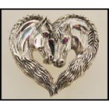 A sterling silver brooch in the form of two horses set with rubies for eyes. Weight approx 19.0g.
