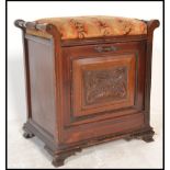 A Victorian mahogany fall front piano stool. The upholstered hinged top over carved panel with