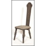 A Victorian carved oak Welsh spinning chair being raised on three legs with carved panel seat and