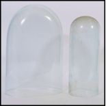 Two glass display domes to include a square sided dome along with a smaller tall cylindrical dome.
