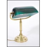 A 20th century brass bankers lamp raised on circular base with adjustable green glass shade. 36cm