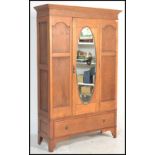 A 20th Century 1920's Edwardian oak wardrobe having a central door with a bevelled oval mirror