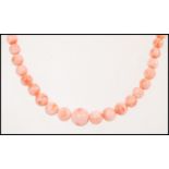 A vintage pink salmon coral bead necklace having a floral gilt clasp.