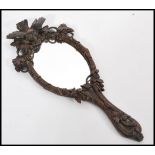 An early 20th century carved Black Forest hand mirror having shaped handle depicting birds. 35cm
