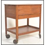 A mid century beech wood veneer sewing box cabinet set on to trolley wheels and raised on squared