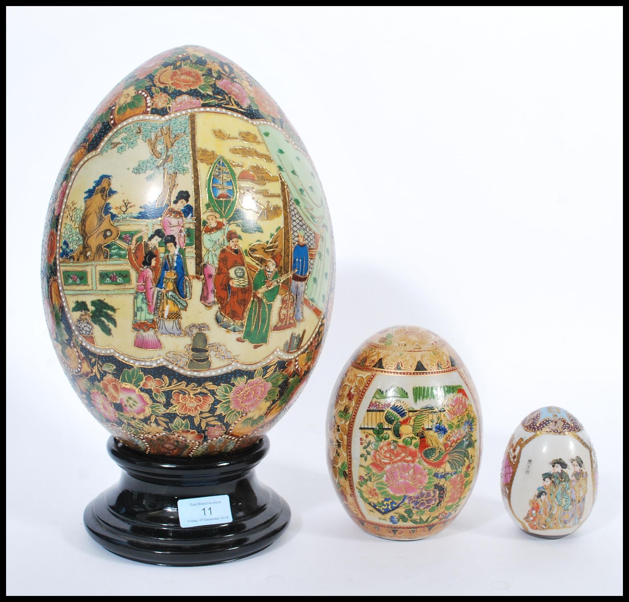 A group of three vintage 20th century Japanese ceramic eggs to include a large example on ebonised