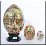 A group of three vintage 20th century Japanese ceramic eggs to include a large example on ebonised