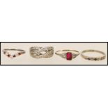 A group of four silver rings to include a crossover ring set with white stones, a wishbone ring