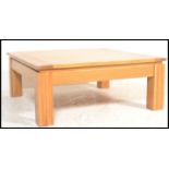 A contemporary large oak coffee - occasional table of square form being raised on well turned legs