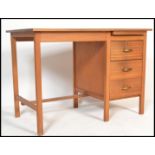 A 1970's teak wood writing table desk of Danish influence being raised on squared legs united by