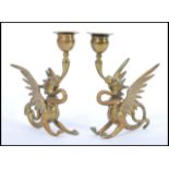 A pair of late 19th century cast brass candlesticks modelled as dragons with wings raised scrolled