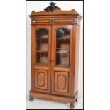 A 19th century walnut cabinet armoire bookcase raised on bun feet with twin glazed doors. Carved