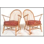 A pair of original mid 20th century Ercol Windsor pattern armchairs having shaped elbow supports