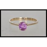A stamped 375 9ct gold ring prong set with an oval cut central pink stone. Weight 1.7g. Size Q.