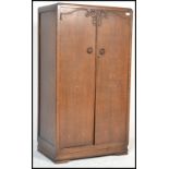 A 1930's Art Deco oak bachelors wardrobe with full length panel door having central embellishment.