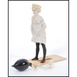 An early 20th century unusual bisque porcelain figurine of a nude lady urinating with remains of