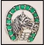 A stamped 925 silver ring in the form of a horseshoe with a horse to the centre set with green