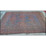 A late 19th / early 20th Century hand woven rug on red ground, geometric borders with a large