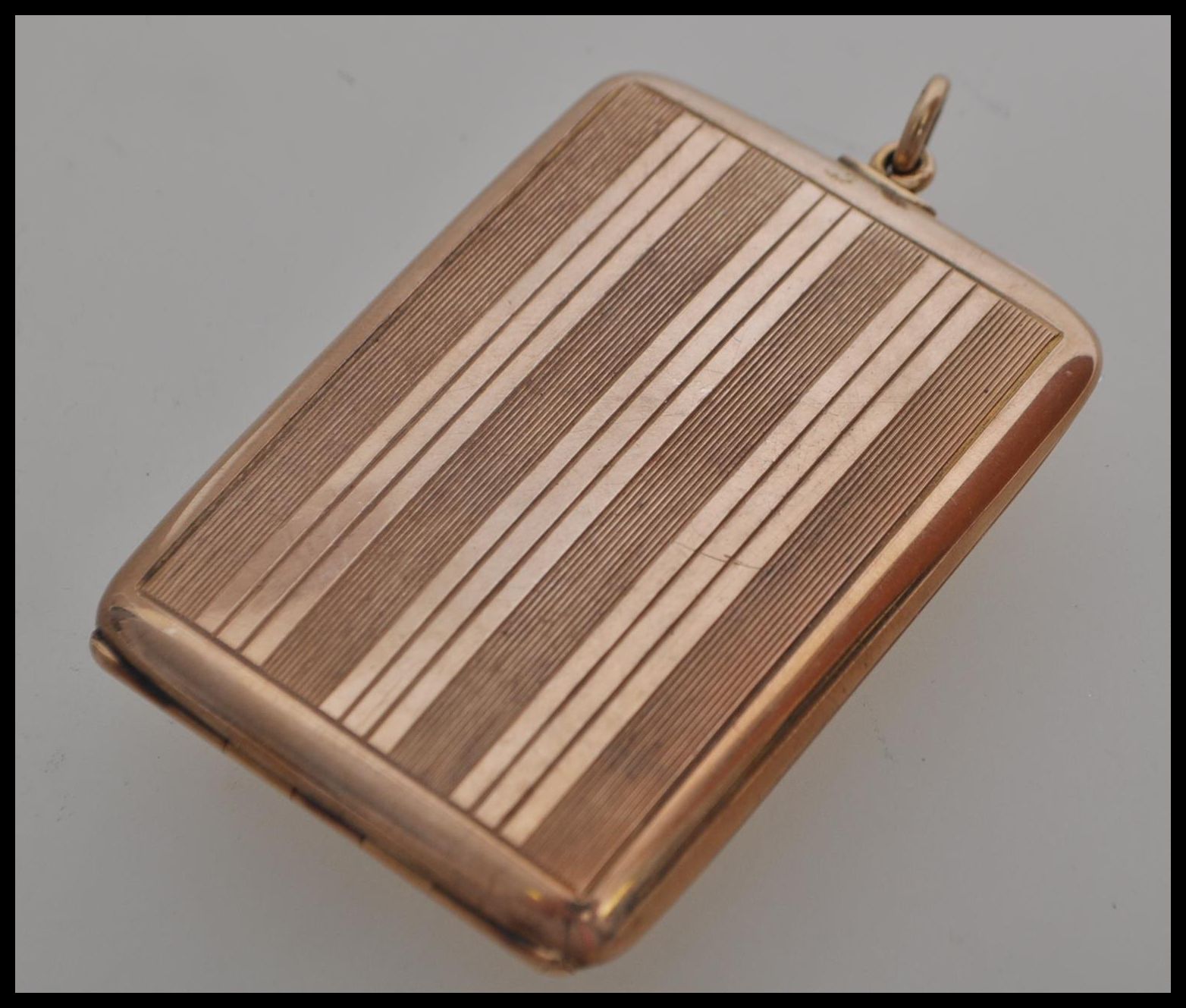 A stamped 375 9ct gold vesta case of square form having striped engraved decoration and loop to