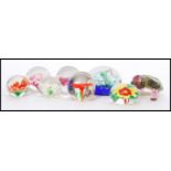 A selection of 20th century glass domed paper weights having glass flowers to the interior, a long